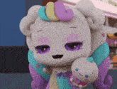 a stuffed animal with purple eyes holds a doll