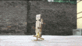 a robot made out of popsicle sticks is walking on a sidewalk in front of a brick wall