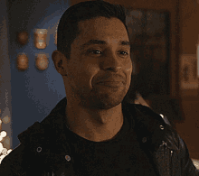 a man wearing a black shirt and a black leather jacket is smiling