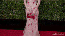 a woman in a pink dress is holding a red clutch bag