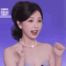 a woman is wearing a pearl necklace and a purple dress .