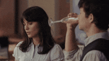 a man is drinking a glass of wine next to a woman