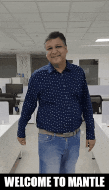 a man in a blue shirt and jeans is standing in an office with the words welcome to mantle on the bottom
