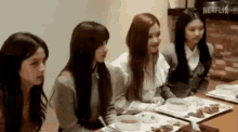 a group of young women are sitting at a table with bowls of food .