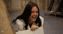 a woman is laughing while holding a piece of paper in her hand .