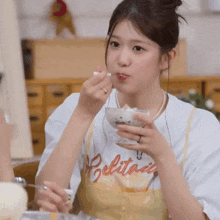 a woman wearing a white shirt with the word belitani on it is eating ice cream