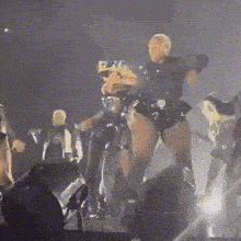 a group of people are dancing on a stage in a dark room with a blurred background .