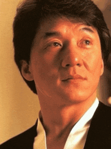 a close up of a man 's face with a black jacket and white shirt
