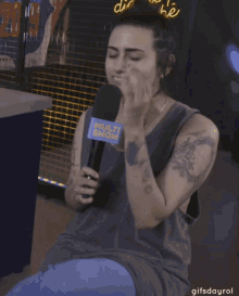 a woman is holding a microphone with a multi show logo on it