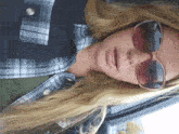 a woman wearing sunglasses and a plaid shirt has her mouth open