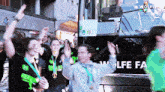 a group of people are standing in front of a bus that says wolfe fa