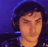 a man wearing headphones is looking at the camera with a serious look on his face .