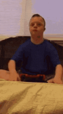 a young boy is sitting on a bed wearing headphones and playing a video game .