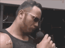 a man wearing sunglasses is holding a microphone and singing into it .