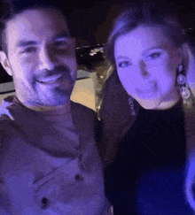 a man and a woman are posing for a selfie in a dark room