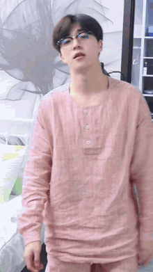 a young man wearing glasses and a pink shirt is standing in front of a flower painting
