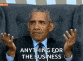 barack obama is sitting in a chair with his hands in the air .