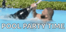 a man is laying in a pool with a bottle of champagne in his hand .
