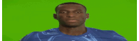 a man in a blue shirt is smiling in front of a green background .