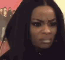 a woman with long black hair is making a funny face while standing in front of a red wall .
