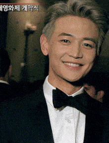 a man wearing a tuxedo and bow tie smiles