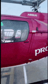 a red airbus pro helicopter is sitting on the ground