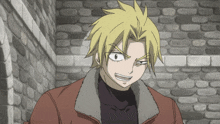 a man with blonde hair is smiling in front of a stone wall