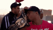 a man in a red shirt kisses the awn wrestling belt