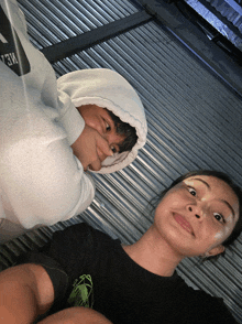 a man wearing a white hoodie with the letter m on it is next to a woman
