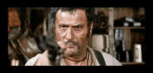 a man with a beard is pointing a gun at the camera in a movie .