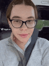 a woman wearing glasses is taking a selfie in a car with the app viggle.ai
