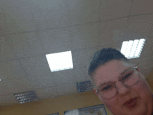 a man wearing glasses is taking a selfie in front of a ceiling