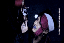 a woman with purple hair is holding a doll and wearing a santa hat