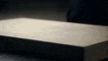 a person is cutting a piece of paper with a knife on a table .