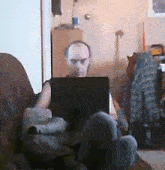 a man sits on a couch using a laptop