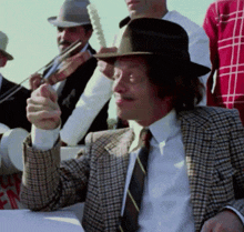 a man wearing a hat and a plaid jacket is playing a musical instrument