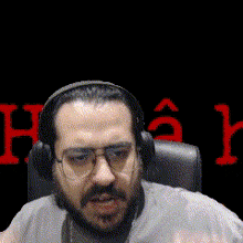 a man wearing headphones and glasses is sitting in a chair with the word hack in the background .