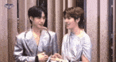 a couple of men are standing next to each other and talking .