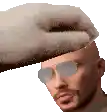 a man wearing sunglasses is being touched by a hand .