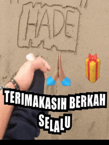the word hade is written in the sand with a person 's hand
