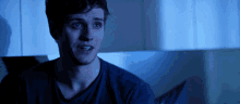 a man in a blue shirt is looking at something in the dark