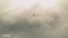 a man in a cape is flying through the clouds with the caption #superman
