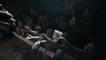 a crowd of people reaching out towards a microphone