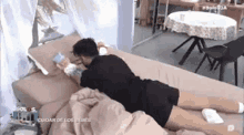 a man is laying on a bed with his legs crossed and holding a book .