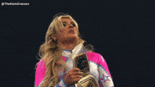 a woman in a pink and white outfit holds a wrestling belt