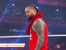 a man in a red tank top is standing in a wrestling ring with a w logo in the corner