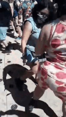 a group of people are dancing on a sidewalk in front of a crowd .