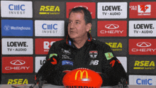 a man holding a red mcdonald 's soccer ball in front of a wall of advertisements