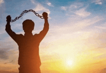 a silhouette of a man holding a chain in his hands in front of a sunset .