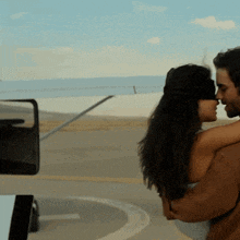 a man is holding a blindfolded woman in his arms while they kiss